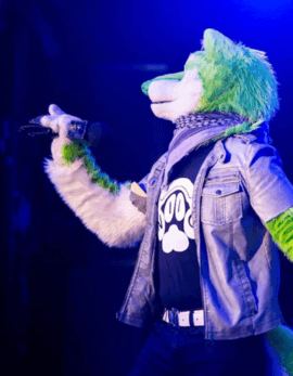 NIIC the Singing Dog on stage with a microphone in blue light